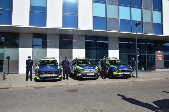 budynek komendy a przed nim trzy oznakowane radiowozy i policjanci stojący obok samochodów