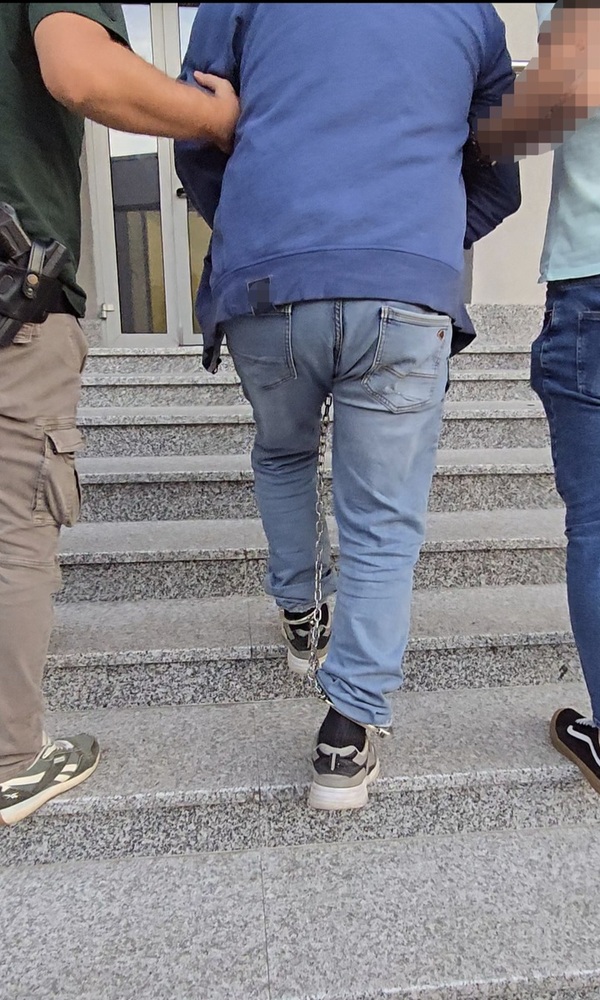 Zatrzymany mężczyzna w trakcie doprowadzenia do jednostki policji.