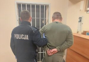 policjant prowadzący zatrzymanego do celi