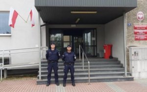 dwoch policjantow pozuje do zdjecia stojac przed wejsciem do Komisariatu Policji Tarnow-Centrum
