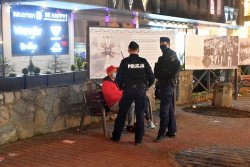 Dwóch policjantów prewencji legitymuje mężczyznę na ławce