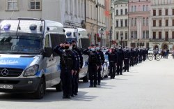 Policjanci ustawieni w szeregu obok radiowozów oddają cześć zmarłemu