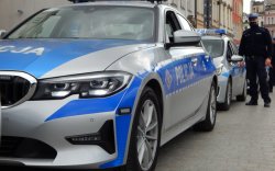 radiowóz marki BMW, w oddali stoi funkcjonariusz policji