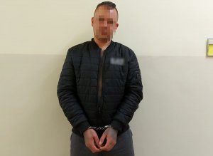 zatrzymany mężczyzna ubrany w czarną kurtkę z założonymi kajdankami