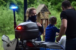 dziecko siedzi na policyjnym motocyklu, obok opiekun oraz policjantka