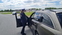 na torze jazdy policjantka stoi przy samochodzie osobowym i rozmawia z kierowcą