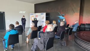 policjantka wewnątrz sali prowadzi zajęcia teoretyczne dla seniorów