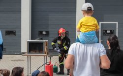 Dziecko na plecach taty ogląda pokaz strażaków
