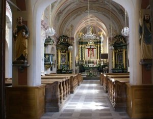 Ołtarz kościoła katolickiego z widocznymi nawami główna i bocznymi oraz ławkami