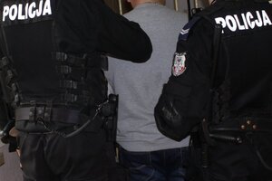 zatrzymany mężczyzna doprowadzany przez dwóch policjantów do pomieszczeń dla zatrzymanych