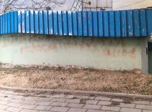 elewacja budynku z naniesionymi zapikselowanymi napisami. Dach budynku obity falista niebieska blachą