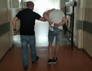 policjant kryminalny prowadzi zatrzymanego mężczyznę