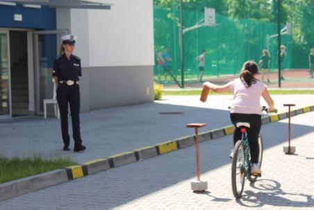 dziewczynka pokonuje tor przeszkód na rowerze w obecności policjantki ruchu drogowego