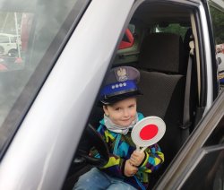 chłopczyk trzyma w ręce tarczę do zatrzymywania pojazdów a na głowie ma czapkę policyjną