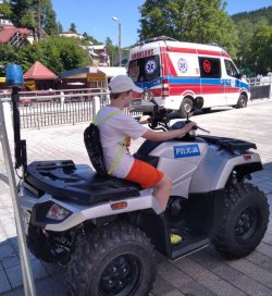 chłopiec siedzący na policyjnym quadzie, w tle ambulans w Krynicy