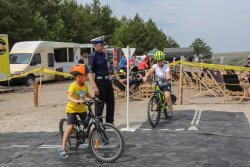 Policjant ruchu instruuje małego rowerzystę na przygotowanym torze. Pustynia