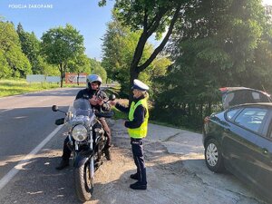 Motocyklista czyta ulotkę. Obok stoi policjantka