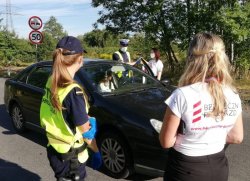 KPP Oświęcim ostatnia wakacyjna akcja  Bezpieczny przejazd   policjant oraz przedstawicielki kolei rozmawiają z kierowcami