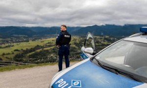 Policjant przy radiowozie patrzy na góry