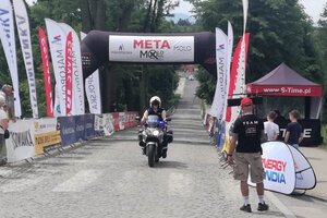 zabezpieczenie wyścigu kolarskiego Molo  Osiek Race 2021  - policjant jadący na motorze po drodze wyścigu, w tle radiowóz, a na poboczu publiczność