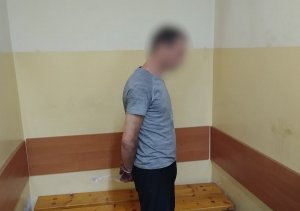 zatrzymany mężczyzna stojący profilem z założonymi kajdankami