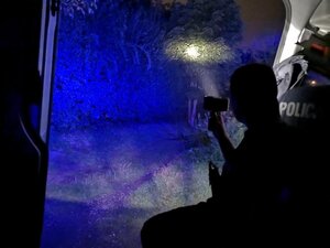 policjant ze szperaczem lustruje okolicę