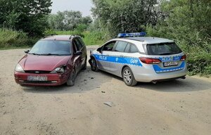 Ford Focus oraz oznakowany radiowóz stojące na szutrowej drodze