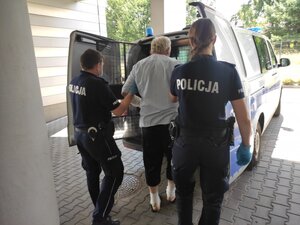 Mężczyzna wprowadzany przez policjantów do radiowozu.