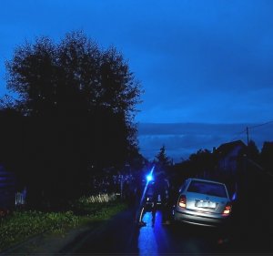 Zdjęcie w porze nocnej. Samochód osobowy marki Skoda. Obok niego na drodze widać zarys stojących osób.