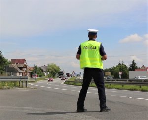 policjant ruchu drogowego nadzoruje ruch na dwujezdniowej drodze