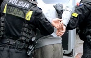 policjanci doprowadzają zatrzymanego do radiowozu