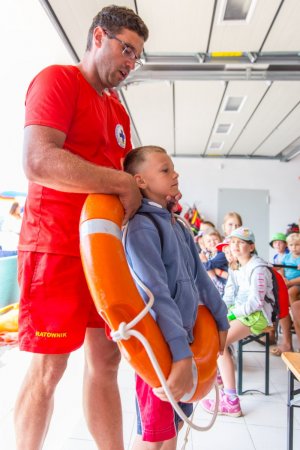 Ratownik pokazuje na dziecku jak pomóc w trakcie tonięcia