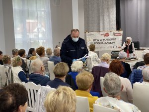 dzielnicowy wręczający ulotki z obostrzeżeniami seniorom