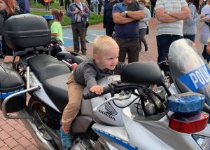 Na zdjęciu widać kilkuletniego chłopca siedzącego na policyjnym motorze Honda