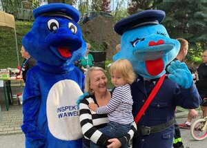 Żywa maskotka „Inspektor Wawelek”, „Polisia” oraz osoba dorosła trzymająca na rękach dziecko