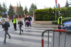 przechodzące przez pasy dzieci w asyście policjantów z ruchu drogowego