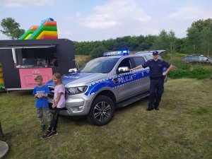 Policjant i dzieci przy radiowozie typu pickap