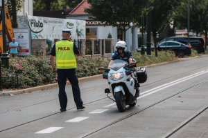 Policjant kieruje ruchem i obok na motocyklu kolejny policjant