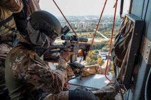 policjant w kabinie śmigłowca mierzy z karabinku