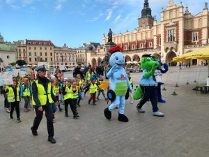 Przemarsz dzieci ubranych w kamizelki odblaskowe ulicami Krakowa w asyście policjantów