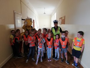 Grupa dzieci z pluszową maskota mrówki i policjantka ruchu drogowego