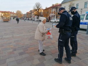 policjanci wręczają starszej kobiecie ulotkę