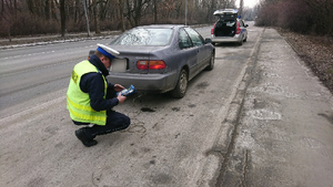 policjant sprawdza wydech pojazdu przy drodze