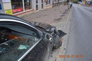 uszkodzone BMW zaparkowane na chodniku, dalej widoczne przewrócone słupki