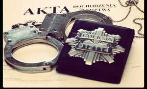 legitymacja policyjna i kajdanki na obwolucie akt dochodzenia
