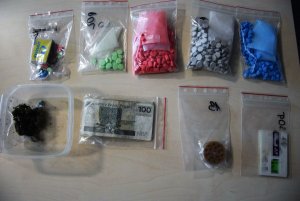 pięć woreczków z zawartością tabletek ecstasy w rożnych kolorach, pudełko z zawartością marihuany oraz gotówka, karty SIM oraz młynek do kruszenia marihuany, zapakowane w woreczkach strunowych