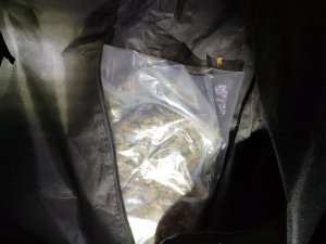 woreczek strunowy z suszem marihuany, wystający z czarnej torby