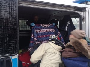 policjantka w radiowozie przekazuje osobie bezdomnej sweter