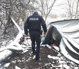 Umundurowany policjant sprawdzający miejsce przebywania osób bezdomnych