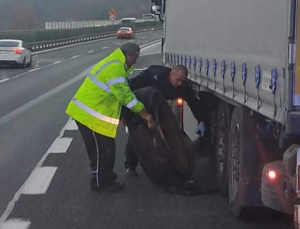policjant pomagający wymienić koło w samochodzie ciężarowym